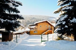 una casa está cubierta de nieve con una valla en Ubytovanie v Súkromi Habovka, en Habovka