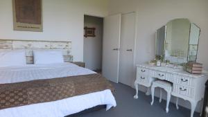 een slaapkamer met een bed en een dressoir met een spiegel bij Kakariki Rooms, Kotare House in Tawharanui