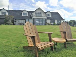 two chairs and a table in front of a house at Kaka Lodge at Kotare House in Tawharanui