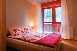 sypialnia z łóżkiem z czerwono-białym kocem w obiekcie Apartamenty Pod Izbicą w mieście Karpacz