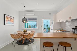 uma cozinha com uma mesa e cadeiras numa cozinha em Bondi Surf Cottage em Sydney