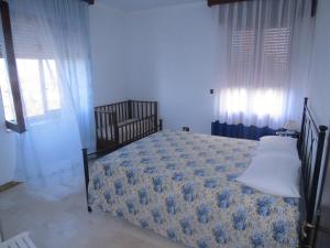 a bedroom with a bed with a blue bedspread and windows at Appartamento Mariolu 3 in Santa Maria Navarrese