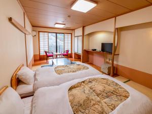 那須塩原市にある塩原温泉 八汐荘のベッド4台、テーブル、テレビが備わる客室です。