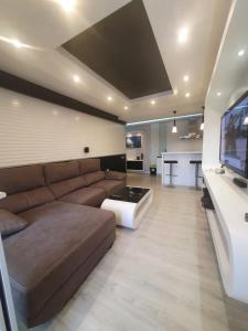 uma sala de estar com um sofá castanho e uma televisão em Bungalows del Golf Almerimar em Almerimar