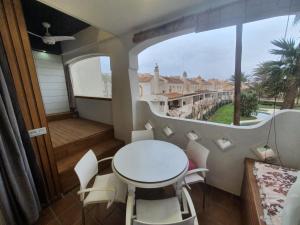 a balcony with a white table and chairs and a window at Bungalows del Golf Almerimar in Almerimar +9 photos
