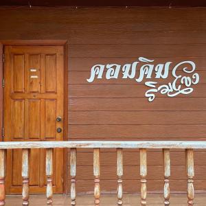 una casa de madera con una puerta y un cartel en ella en คอมคิม ริมโขง เชียงคาน, en Loei
