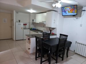 cocina con mesa y sillas y TV en la pared en Departamento Eutico en Villa Carlos Paz