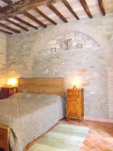 sypialnia z łóżkiem i kamienną ścianą w obiekcie Casa Julia con giardino e piscina privati w mieście Chianni