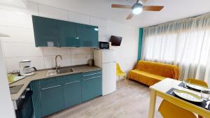 a kitchen with blue cabinets and a yellow couch at Apartamentos Eldorado in Lloret de Mar