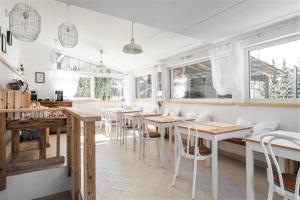 a restaurant with wooden tables and white chairs at Villa Milimani - stuletnia, folk & butique, adults only in Zakopane