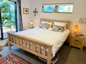 a bedroom with a large bed with a window at Palm Garden Beach House in Papamoa