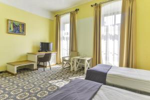 una camera d'albergo con 2 letti, una scrivania e una TV di Hotel Sighişoara a Sighişoara