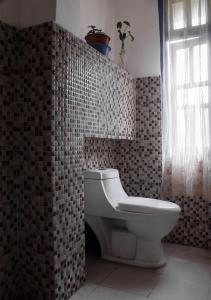 a bathroom with a toilet and a tile wall at Ashraya Boutique Homestay in Rongli