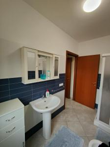 a bathroom with a white sink and blue tiles at Appartamenti RoccaForte MONO BLU Trapani in Milo