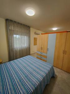 een slaapkamer met een bed met een blauw gestreepte deken bij Appartamenti RoccaForte MONO BLU Trapani in Milo