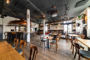 ein Restaurant mit Holztischen und -stühlen und einer Bar in der Unterkunft De BrauHotel in Niederkerschen