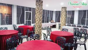 un restaurante con mesas rojas y sillas negras en Chunmun Cottage en Pachmarhī