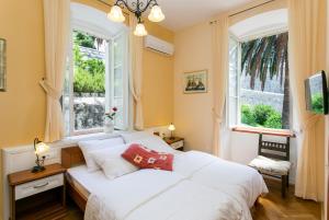 a bedroom with two white beds and two windows at Rooms Posat in Dubrovnik