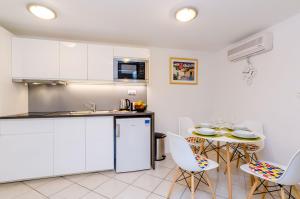 a kitchen with white cabinets and a table and chairs at Apartment Domix in Dubrovnik