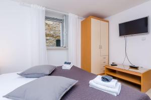 a bedroom with a bed with a tv on the wall at Apartment Domix in Dubrovnik