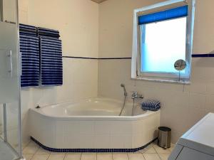 La salle de bains est pourvue d'une baignoire blanche et d'une fenêtre. dans l'établissement Haus Glücksmoment, à Sankt Englmar