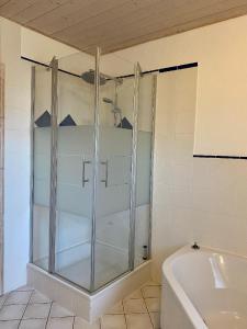 La salle de bains est pourvue d'une douche en verre et d'une baignoire. dans l'établissement Haus Glücksmoment, à Sankt Englmar