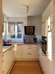 a kitchen with white cabinets and a flat screen tv at Haus Glücksmoment in Sankt Englmar