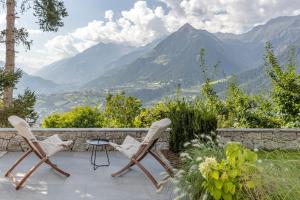 2 sillas y una mesa en un patio con montañas en Michael Am Waal, en Scena