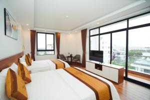 Habitación de hotel con 2 camas y TV de pantalla plana. en Realux Hotel en Sầm Sơn