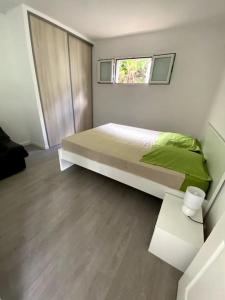 una camera da letto con letto con lenzuola verdi e finestra di Maison accueillante, quartier verdoyant a Sainte-Marie