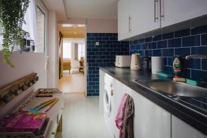 a kitchen with a sink and blue tiles at Salt Life Cottage in Brighton & Hove