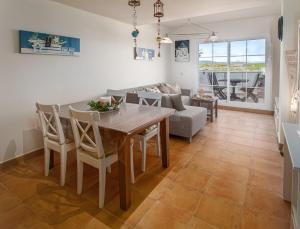 Terrazas de Alcaidesa 2361 في ألكيديسا: غرفة طعام وغرفة معيشة مع طاولة وكراسي