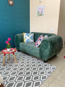 a green couch in a living room with a table at Elegant and cozy studio apartment in Nairobi Ruaka in Ruaka