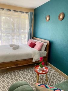a bedroom with a bed and a blue wall at Elegant and cozy studio apartment in Nairobi Ruaka in Ruaka