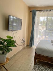 a bedroom with a bed and a tv on the wall at Elegant and cozy studio apartment in Nairobi Ruaka in Ruaka
