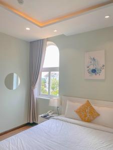 a bedroom with a white bed and a window at THE VILLA HIEU HY in Quy Nhon