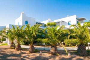 a row of palm trees in front of a building at Nissiotiko Studios & Apartments in Drios