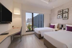a hotel room with two beds and a desk and a window at 7 Apple Hotel Mahape, Navi Mumbai in Navi Mumbai