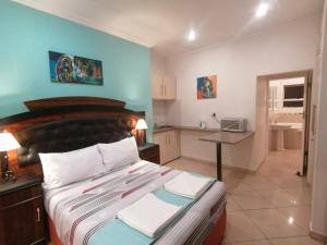 a bedroom with a large bed and a kitchen at Palm View Guest House in Pretoria