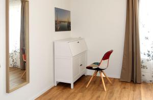 a white cabinet and a red chair in a room at Windwatt in Gollwitz