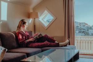 a woman sitting on a couch reading a book at Victoria Hotel Kragerø in Kragerø