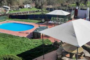a white umbrella sitting next to a swimming pool at ALOJAMIENTO ENTERO CON PISCINA Y JARDIN. in Ourense
