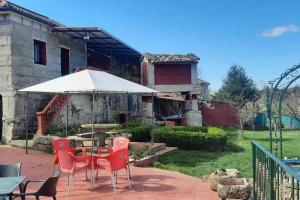a patio with a table and chairs and an umbrella at ALOJAMIENTO ENTERO CON PISCINA Y JARDIN. in Ourense