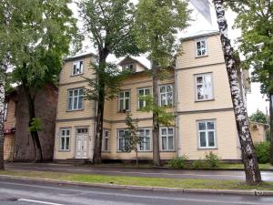 a yellow house with trees in front of a street at Supeluse Apartments in Pärnu