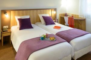 two beds in a hotel room with a tray of food at Brit Hotel Reims Croix Blandin in Reims