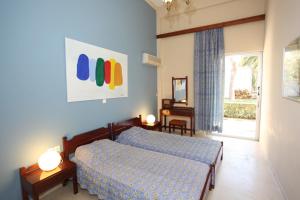 a blue bedroom with a bed and a window at Ballos Apartments in Nea Makri