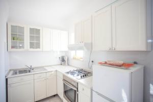 - une cuisine blanche avec évier et cuisinière dans l'établissement Apartments and Room Agata, à Banjole