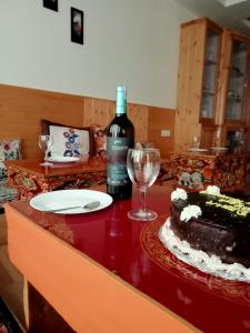 列城的住宿－Hotel Jigmet, Leh，坐在桌子上的一瓶葡萄酒,还有蛋糕和一杯