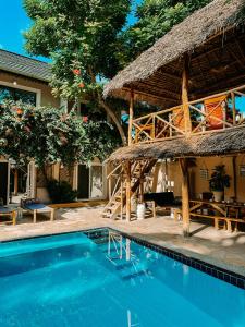 a resort with a swimming pool and a thatched building at Ebb & Flow in Paje