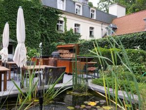 a garden with a pond and a table and umbrella at Le Domaine de Beaulieu in Busnes